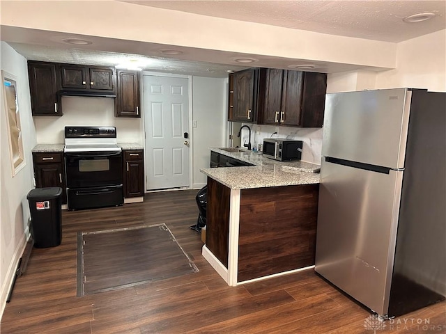 1566 Cora St, Springfield, OH 45503 - kitchen with appliances with stainless steel finishes, dark wood-style floors, dark brown cabinets, light stone counters, and a peninsula