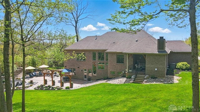 rear view of house featuring a patio, a chimney, a yard, and brick siding