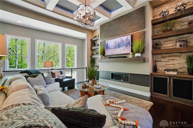 living room with an inviting chandelier, a glass covered fireplace, dark wood-style floors, and a healthy amount of sunlight