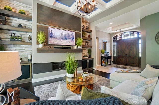 living area featuring a glass covered fireplace, wood finished floors, baseboards, recessed lighting, and a notable chandelier