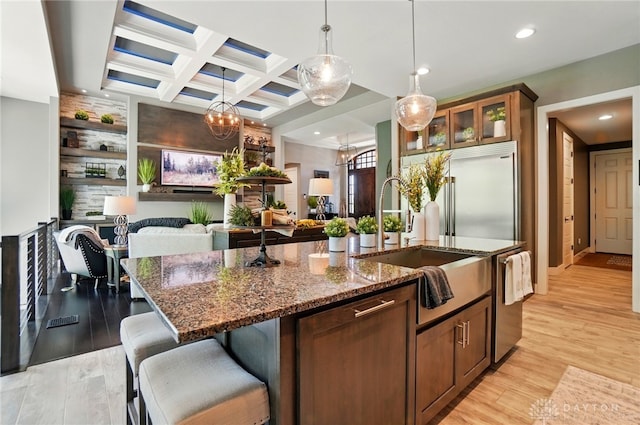 kitchen featuring a kitchen island with sink, recessed lighting, dark stone countertops, and light wood-style floors