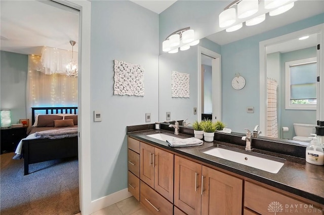 ensuite bathroom featuring double vanity, a notable chandelier, a sink, and ensuite bathroom