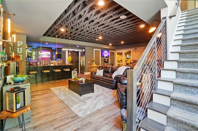 living room with stairs, wood finished floors, and bar area