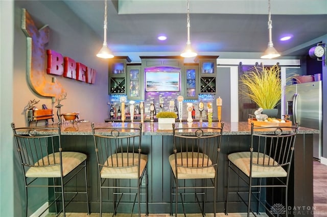 bar with stainless steel fridge, recessed lighting, wet bar, and pendant lighting