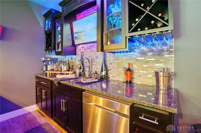 bar with a dry bar, tasteful backsplash, wood finished floors, dishwasher, and a sink