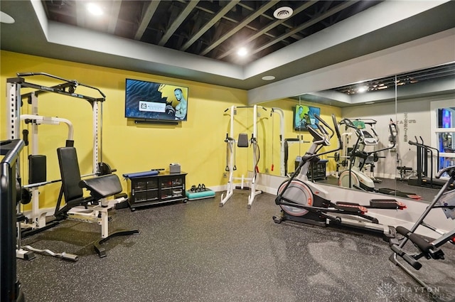 workout area with baseboards and a tray ceiling