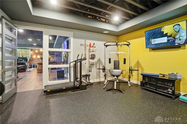 workout area with baseboards and a tray ceiling