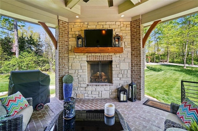 view of patio with an outdoor stone fireplace, a ceiling fan, and a grill