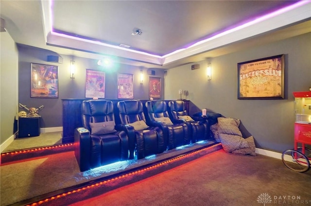 carpeted cinema featuring a raised ceiling and baseboards