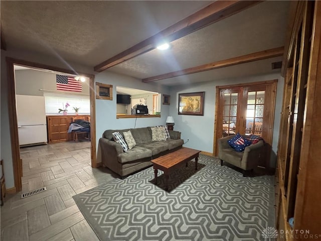 living room featuring french doors, a textured ceiling, beamed ceiling, and a wealth of natural light