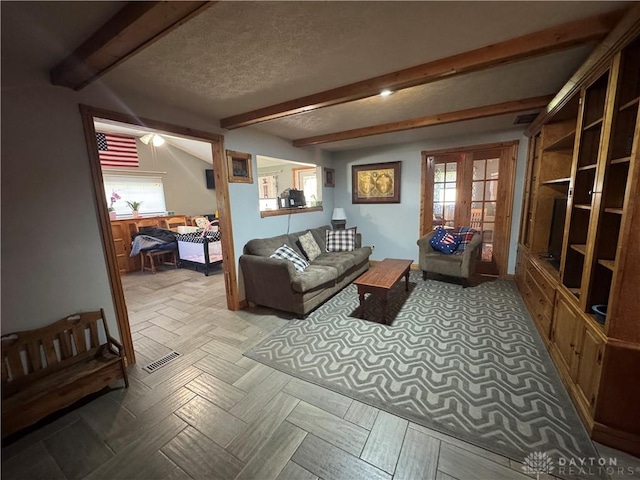 living room with visible vents, a textured ceiling, plenty of natural light, and beam ceiling