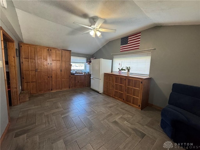 bedroom featuring ceiling fan, a textured ceiling, freestanding refrigerator, baseboards, and vaulted ceiling