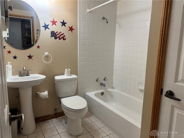 bathroom with a sink, toilet, tile patterned floors, baseboards, and  shower combination