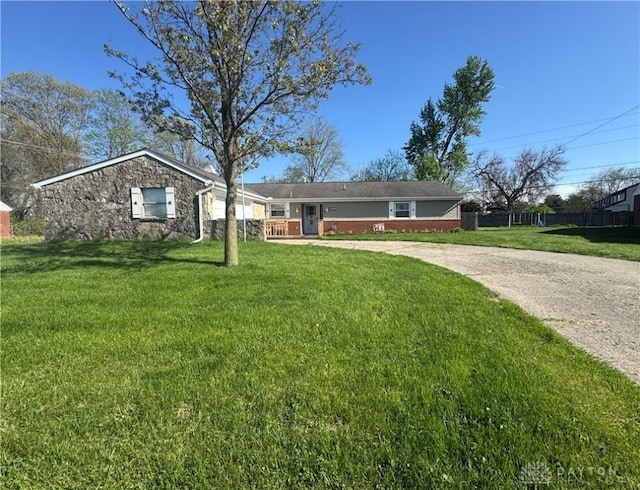 ranch-style house with concrete driveway, stone siding, and a front lawn