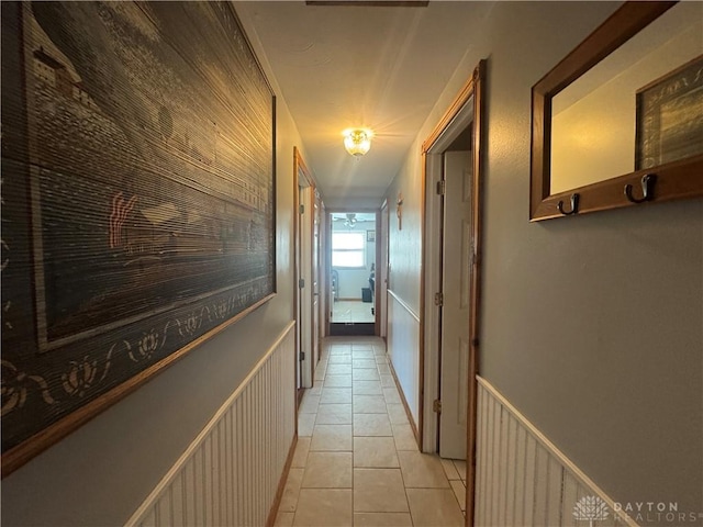 hallway with light tile patterned flooring and wainscoting