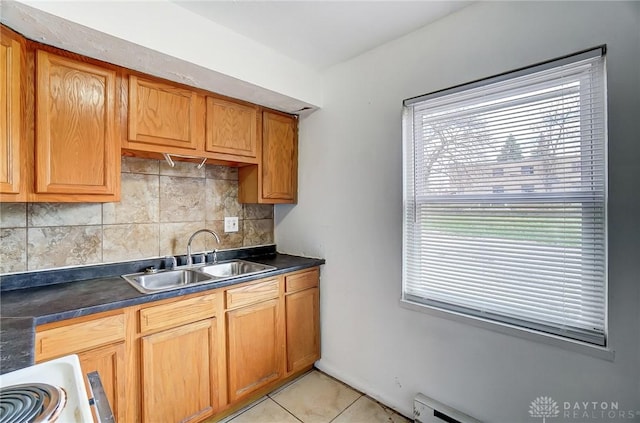 2334 Davue Cir, Dayton, OH 45406 - kitchen with light tile patterned flooring, dark countertops, a sink, brown cabinetry, and decorative backsplash