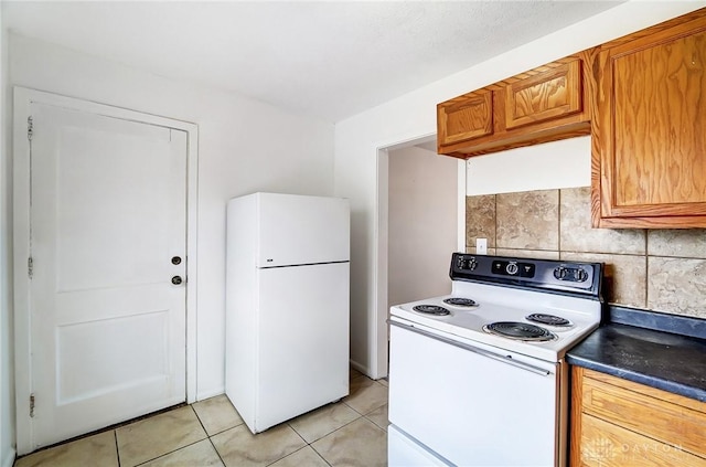 2334 Davue Cir, Dayton, OH 45406 - kitchen with dark countertops, white appliances, light tile patterned floors, brown cabinets, and backsplash