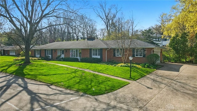 single story home featuring a chimney, driveway, a front lawn, and brick siding