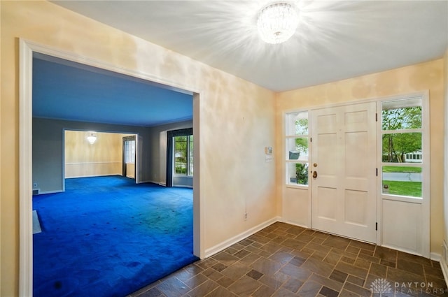 entrance foyer with baseboards and dark colored carpet
