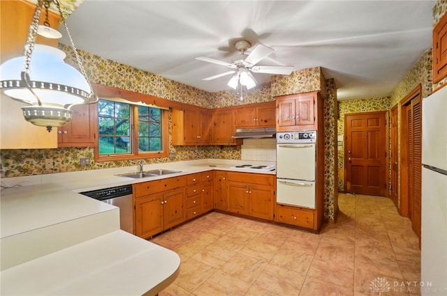kitchen featuring decorative backsplash, white appliances, wallpapered walls, light countertops, and a sink