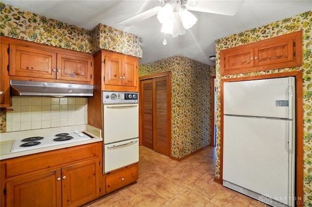 kitchen featuring backsplash, light countertops, under cabinet range hood, wallpapered walls, and white appliances