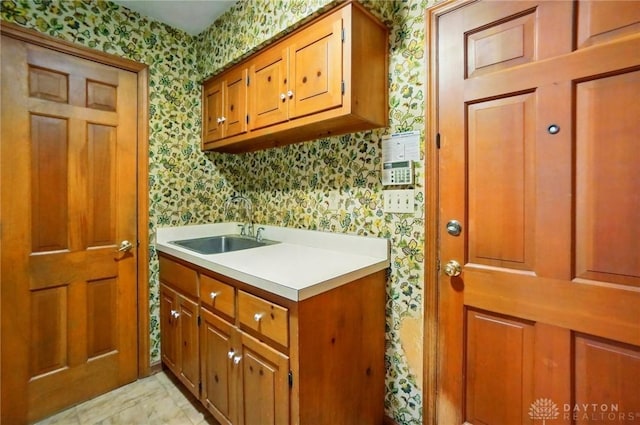 washroom featuring a sink and wallpapered walls