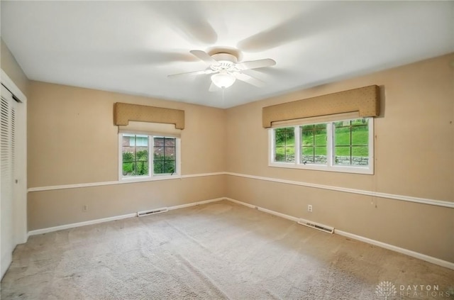 empty room featuring carpet flooring, ceiling fan, visible vents, and baseboards