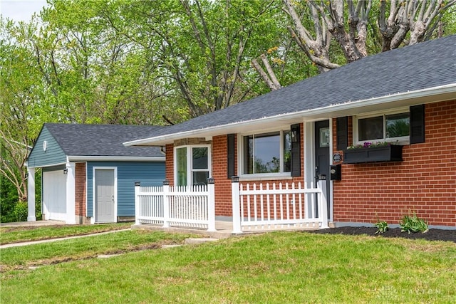 ranch-style home with brick siding, an outbuilding, a shingled roof, and a front yard