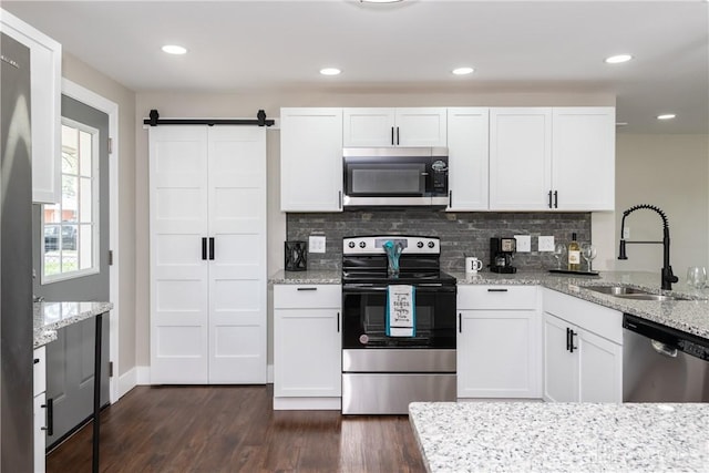 kitchen featuring appliances with stainless steel finishes, tasteful backsplash, dark wood finished floors, a sink, and white cabinetry