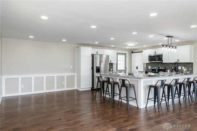 kitchen featuring recessed lighting, appliances with stainless steel finishes, a breakfast bar area, and a peninsula