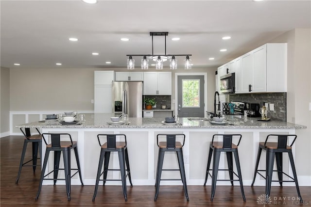 kitchen with a sink, stainless steel appliances, white cabinetry, a peninsula, and tasteful backsplash