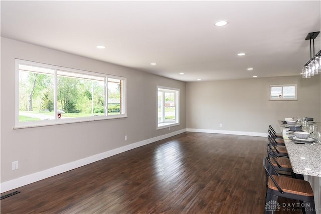 interior space with plenty of natural light, baseboards, and dark wood-style flooring