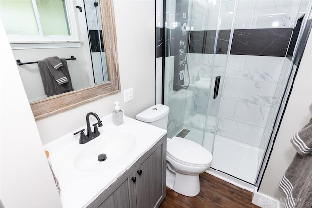 bathroom featuring vanity, a shower stall, toilet, and wood finished floors