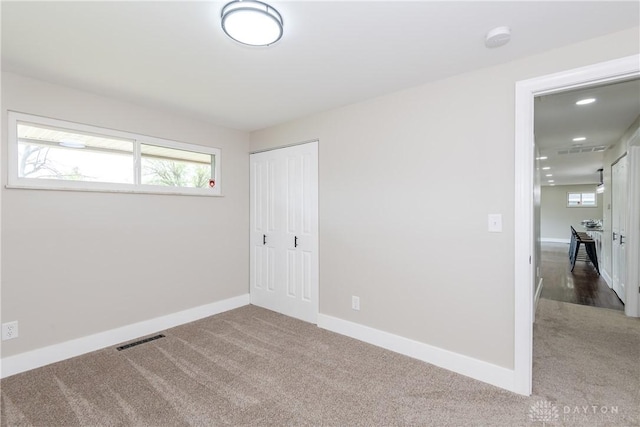unfurnished bedroom featuring baseboards, visible vents, carpet, and a closet