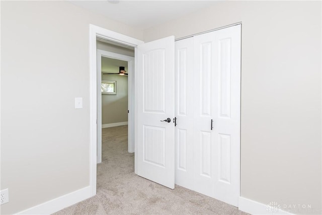 unfurnished bedroom featuring baseboards, a closet, and light colored carpet