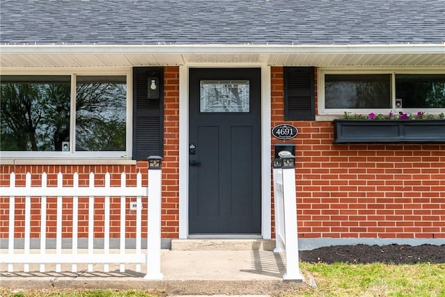 entrance to property with brick siding and roof with shingles