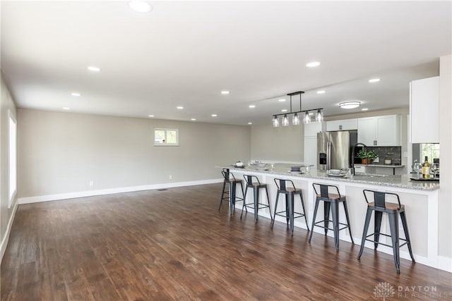 kitchen featuring stainless steel fridge with ice dispenser, a breakfast bar area, recessed lighting, and white cabinetry