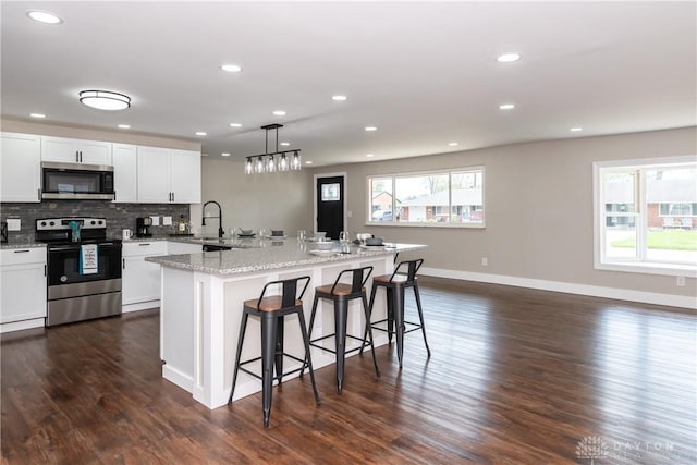kitchen featuring recessed lighting, baseboards, stainless steel appliances, and a kitchen bar