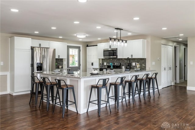 kitchen featuring dark wood-style flooring, stainless steel appliances, decorative backsplash, and a peninsula