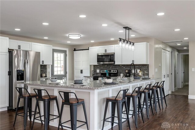 kitchen featuring decorative backsplash, appliances with stainless steel finishes, a peninsula, recessed lighting, and white cabinetry