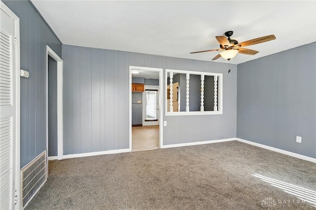 empty room with carpet floors, a ceiling fan, and baseboards