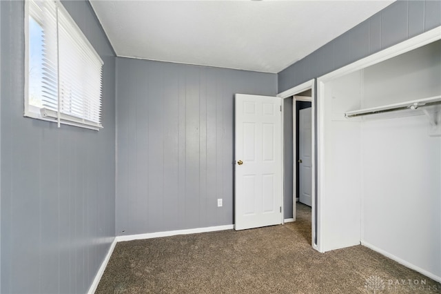 unfurnished bedroom with baseboards, a closet, and dark carpet
