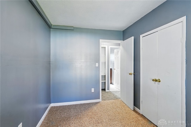 unfurnished bedroom with carpet floors, baseboards, and a closet
