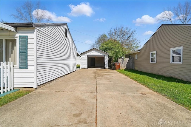 view of side of home with a detached garage, fence, an outbuilding, and concrete driveway