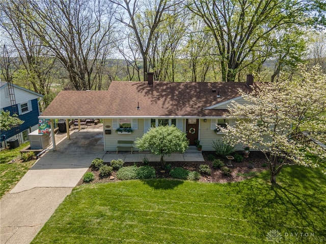 ranch-style home featuring a chimney, roof with shingles, a carport, a front lawn, and concrete driveway