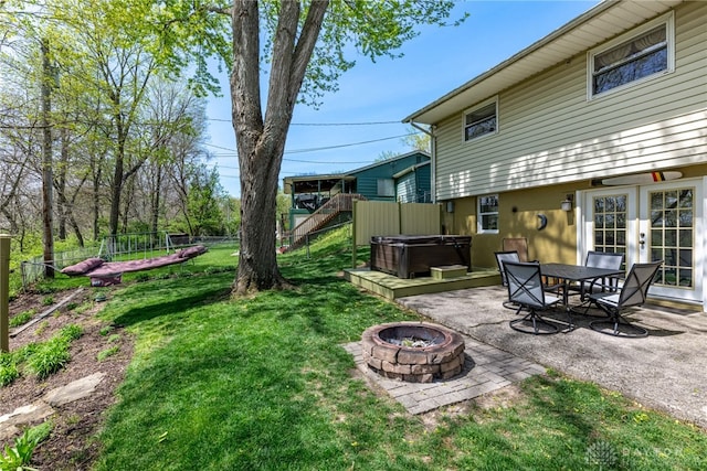 view of yard with a fenced backyard, a hot tub, a patio area, and an outdoor fire pit