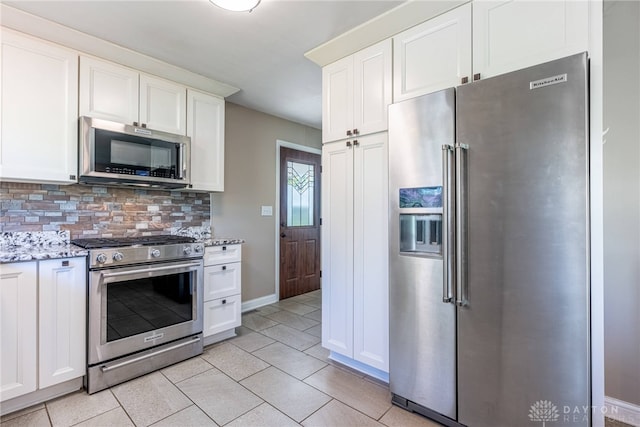 kitchen with appliances with stainless steel finishes, tasteful backsplash, light stone countertops, and white cabinets