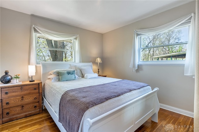 bedroom with baseboards, multiple windows, and hardwood / wood-style floors