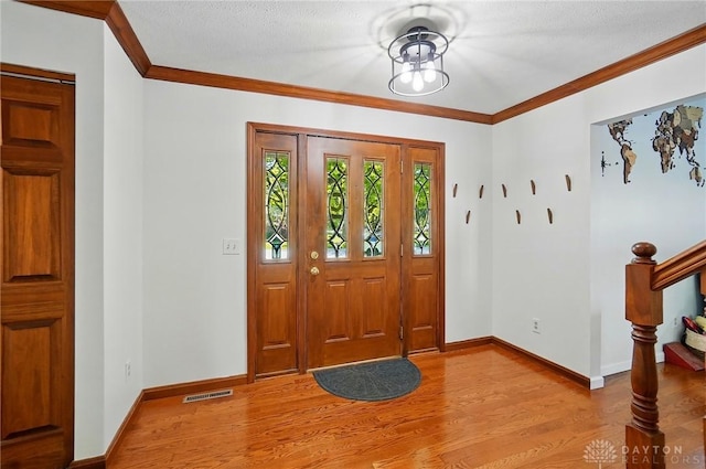 entrance foyer featuring crown molding, light wood-style floors, stairs, baseboards, and visible vents