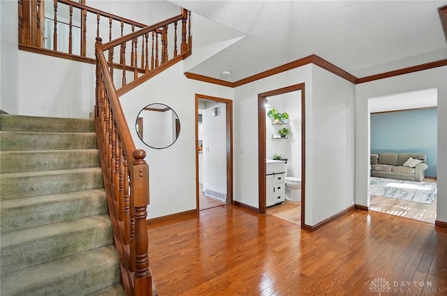 stairs with baseboards, ornamental molding, and wood finished floors